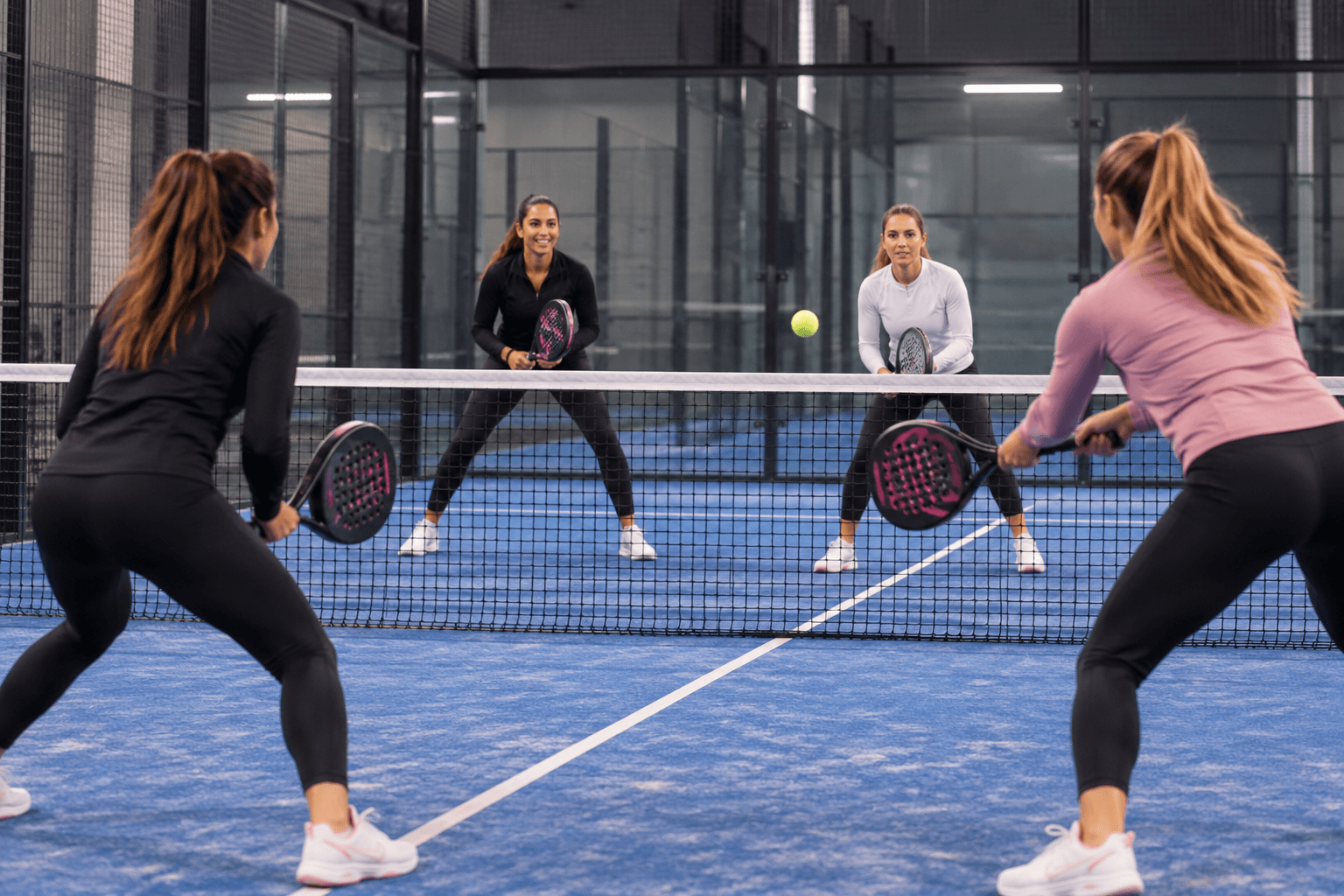 Quatre joueuses de padel sur un terrain couvert